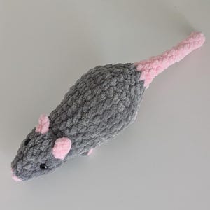 A top down view of a dark gray crochet rat plushie.