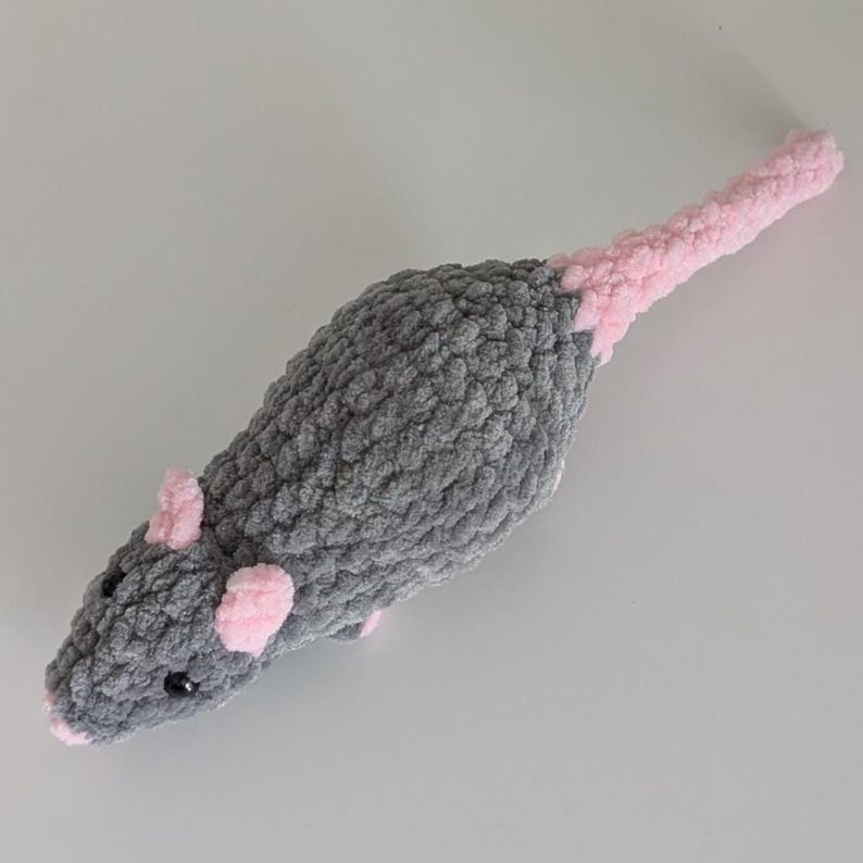 A top down view of a dark gray crochet rat plushie.