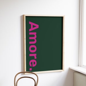 May include: A framed poster with a dark green background and the word "Amore." written in pink vertical text.