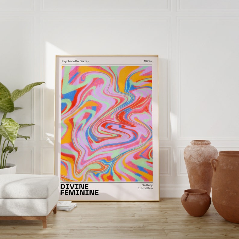 May include: A colorful abstract print with swirling patterns in shades of pink, red, yellow, blue, and green. The print is titled "Divine Feminine" and is part of the "Psychedella Series" from the 1970s. The print is framed and displayed in a room with a white wall and a couch.