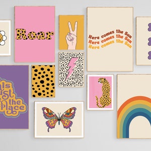 May include: A set of nine colorful wall prints with various designs, including a rainbow, a cheetah, a butterfly, a lightning bolt, a peace sign, a daisy, a flower, and text that says "Roar" and "This Must Be The Place".