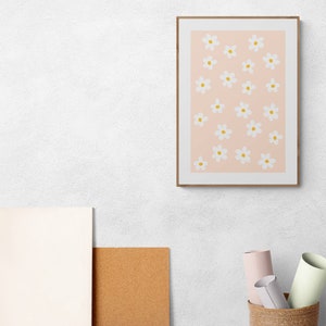 May include: A framed print with a pink background and a pattern of white flowers with yellow centers.