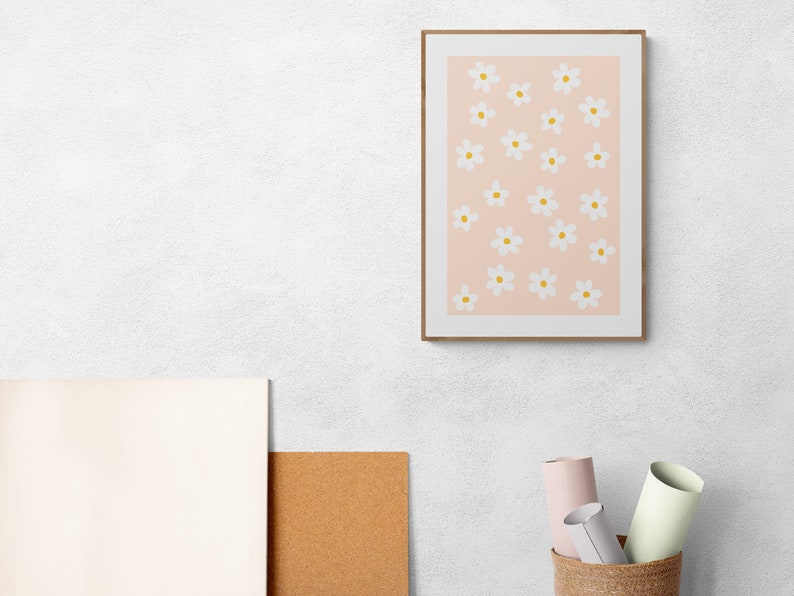 May include: A framed print with a pink background and a pattern of white flowers with yellow centers.