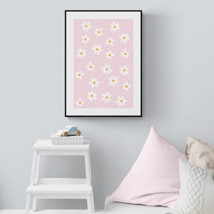 May include: A framed print with a pink background and white flowers with yellow centres. The print is hanging on a light grey wall.