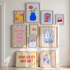 May include: A collection of framed art prints with various designs. Prints include a lemon with "LIMON CELLO", a blue vase with flowers, a red lobster, cherries, "BETTER LATE THAN UGLY", "Ciao Bella", a bikini, sardines, "HOW LUCKY ARE WE?", and "DON'T ASK JUST POUR".