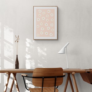 May include: A light wood desk with a white lamp, a chair, and a framed print of white flowers on a pink background.