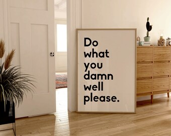 May include: A framed art print with the text "Do what you damn well please" in bold black letters on a cream background. The print is displayed in a room with a wooden cabinet and a houseplant.