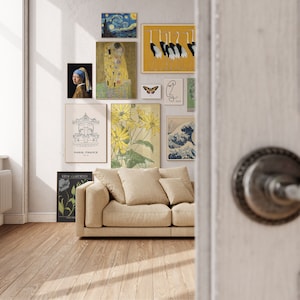 May include: A living room interior with a beige sofa and several framed prints on the wall. The prints include a floral design, a carousel, a starry night scene, a couple kissing, a group of birds, and a wave design. The wall is painted white and the floor is a light wood.
