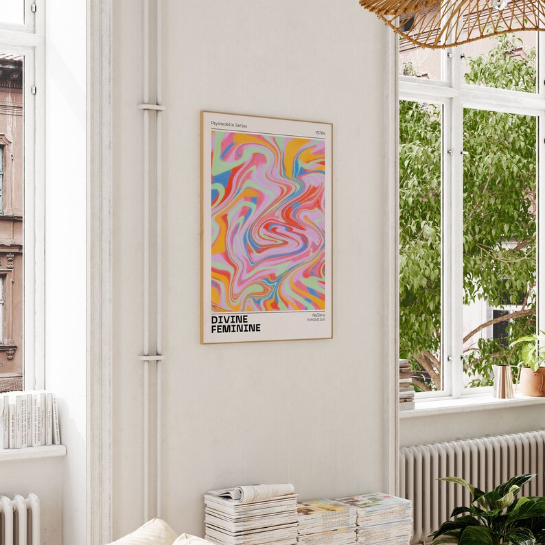 May include: A framed poster with a colorful abstract design in shades of pink, blue, yellow, and green. The text "DIVINE FEMININE" is printed in black at the bottom of the poster.