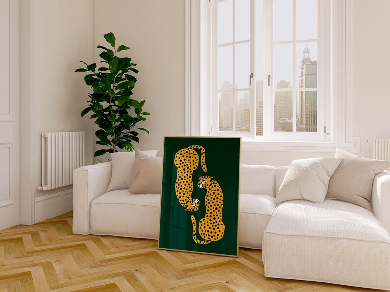 May include: A framed print of two stylized cheetahs in orange and black on a dark green background. The print is hanging on a white wall in a living room setting.