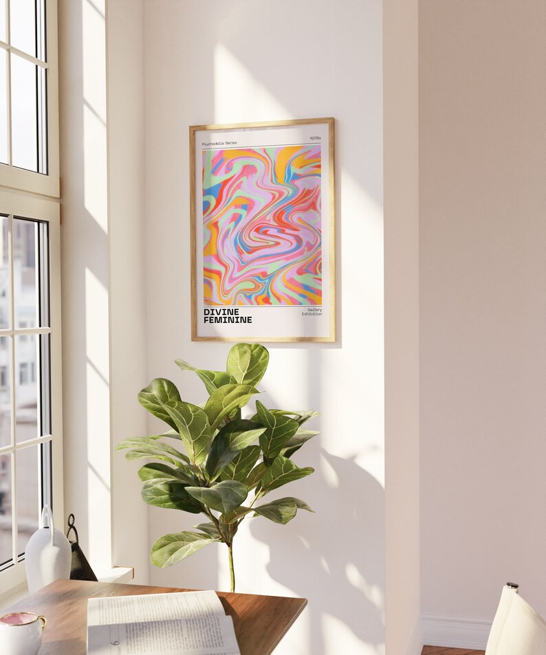 May include: A framed print with a colorful abstract design in shades of pink, yellow, blue, and green. The text "DIVINE FEMININE" is printed below the design.