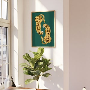 May include: A framed print of two cheetahs in a curled position on a teal green background. The cheetahs are yellow with black spots.