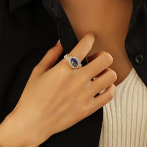 May include: A silver ring with a blue oval gemstone set in a wire-wrapped design.