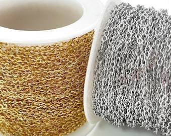 Könnte beinhalten: Zwei Spulen mit Ketten, eine goldfarbene und eine silberfarbene. Die Ketten bestehen aus kleinen, miteinander verbundenen Gliedern. Die Spulen sind weiß und haben eine runde Form, wobei die Kette um sie gewickelt ist.