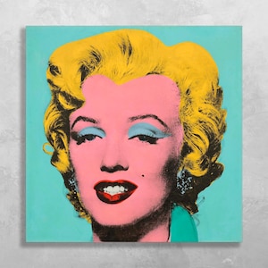 以下が含まれることがあります： マリリン・モンローのポップアートの肖像画。黄色い髪、ピンクの肌、青いアイシャドウ、赤い唇が特徴です。作品はターコイズブルーの背景で、象徴的な女優の鮮やかでカラフルな描写です。