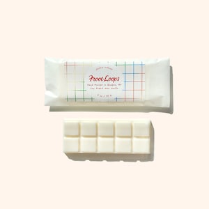 Op de afbeelding: Een witte was smeltbalk met 9 vierkanten, met het label "Froot Loops" en een kleurrijk rasterpatroon op de verpakking. Handgegoten sojawas smelttabletten uit Queens, NY. 2 oz / 56 g.