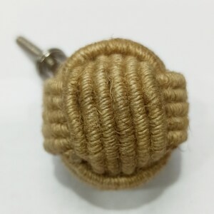 Op de afbeelding: Een ronde, bruine, met touw omwikkelde kastknop met een zilveren schroef.