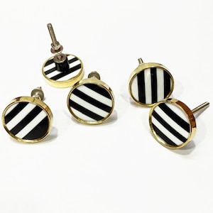 May include: Five black and white striped round cabinet knobs with gold metal trim.