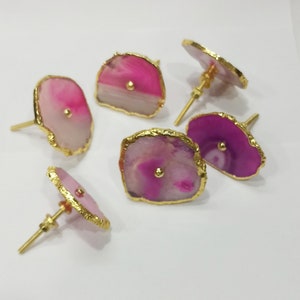 Op de afbeelding: Vijf roze en paarse agaat-ladegrepen met gouden rand. Elke greep heeft een kleine gouden knop in het midden.