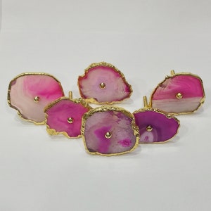 Op de afbeelding: Zes roze en witte agaat-ladegrepen met gouden rand. Elke greep heeft een gouden knop in het midden.