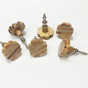 May include: Six wooden drawer pulls with a white and brown striped design. The pulls are shaped like a flower with five petals.