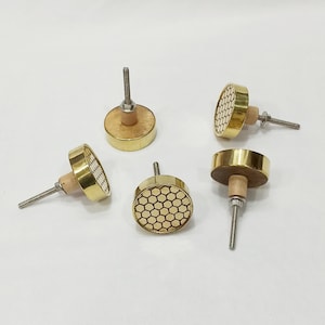 May include: Five gold and wood cabinet knobs with a honeycomb pattern. The knobs have a round shape and a small screw on the back.