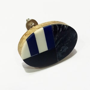 May include: Oval-shaped cabinet knob with a wood base and a blue and white geometric design.