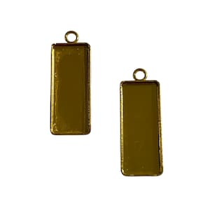 May include: Two gold-coloured rectangular pendant trays with a loop at the top for attaching to a chain or cord. The trays have a shiny, reflective surface and are empty, ready for embellishment.