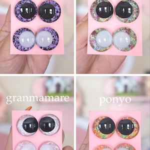 May include: Four sets of decorative doll eyes on pink cards. Each set includes two black and two white eyes with glittery, colorful borders. The sets are labeled "kaonashi", "arrietty", "granmamare", and "ponyo".