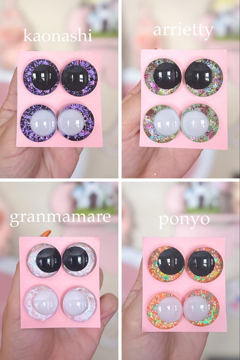 May include: Four sets of decorative doll eyes on pink cards. Each set includes two black and two white eyes with glittery, colorful borders. The sets are labeled "kaonashi", "arrietty", "granmamare", and "ponyo".