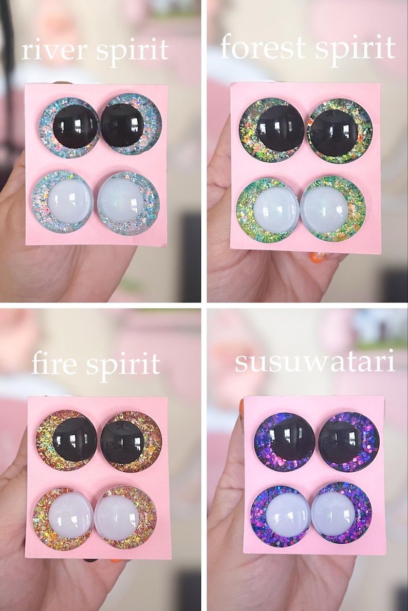 May include: Four sets of decorative glass eyes on pink cards, each labeled with a different theme: "river spirit," "forest spirit," "fire spirit," and "susuwatari." The eyes have black or white centers with glittery, colorful rims.