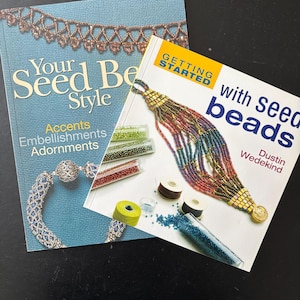 Könnte beinhalten: Zwei Bücher auf einer schwarzen Oberfläche. Ein Buch trägt den Titel "Your Seed Bead Style" mit Akzenten, Verzierungen und Ornamenten. Das andere Buch trägt den Titel "Getting Started with Seed Beads" von Dustin Wedekind.