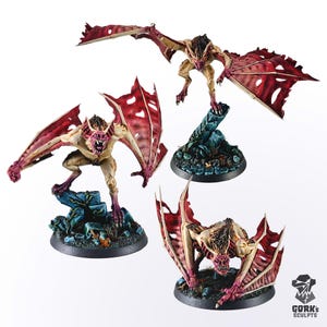 Pode incluir: Três figuras em miniatura pintadas de criaturas semelhantes a morcegos com asas vermelhas e brancas. As figuras estão em diferentes posições e estão em pé sobre bases circulaires.