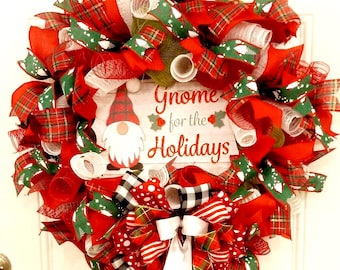 May include: A festive Christmas wreath with red, green, and white ribbons and mesh. The wreath features a wooden sign with a gnome illustration and the text "Gnome for the Holidays". The wreath is hanging on a white door.