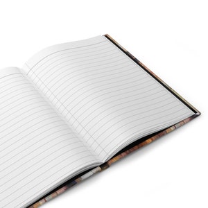 May include: Open journal with lined pages. The journal's pages are white with thin gray lines. The cover has a colorful, textured design with shades of brown, orange, and black. The journal is open, revealing the blank pages.