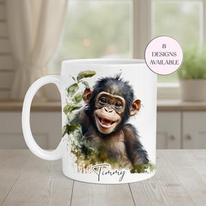 May include: White ceramic mug featuring a smiling chimpanzee illustration with green foliage accents. The mug has a curved handle and the name "Timmy" is written in script. A pink circle indicates "8 designs available".
