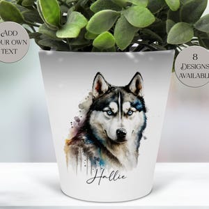 Könnte beinhalten: Weiße Keramik-Pflanzschale mit einem Aquarellporträt eines Siberian Huskys mit blauen Augen. Der Topf trägt den Namen "Hallie" in Schreibschrift und zwei runde Textaufkleber mit der Aufschrift "Add Your Own Text" und "8 Designs Available".