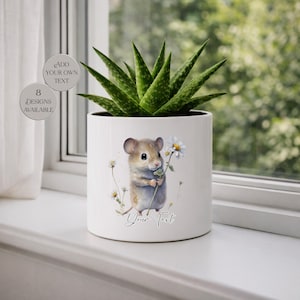 May include: White ceramic planter with a watercolor illustration of a mouse holding a daisy. The planter contains a green succulent plant. Text on the planter reads "Add Your Own Text" and "8 Designs Available".