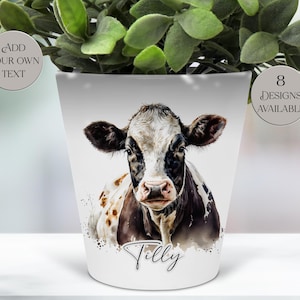May include: White ceramic plant pot with a watercolour-style image of a cow with black and white markings. The cow is centered, with the name "Tilly" below. Text on the pot reads "Add Your Own Text" and "8 Designs Available".
