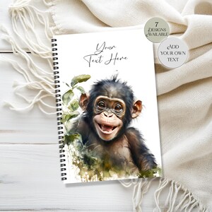 May include: A spiral-bound notebook featuring a watercolor illustration of a smiling chimpanzee. The cover includes the text "Your Text Here" and two circular design options: "7 Designs Available" and "Add Your Own Text".