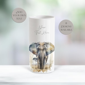 May include: A white cylindrical vase featuring a watercolor painting of an elephant with tusks and large ears. The text "Your Text Here" is written on the vase. The image also includes the text "Add Your Own Text" and "8 Designs Available".