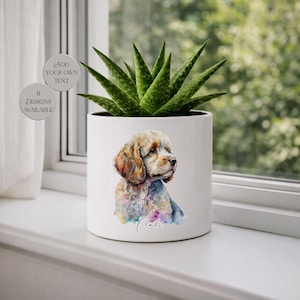 May include: White ceramic planter with a watercolor illustration of a dog, featuring brown, tan, and blue hues. The planter holds a green succulent plant. Text on the planter reads "Cali". Additional text on the left says "Add your own text" and "8 designs available".