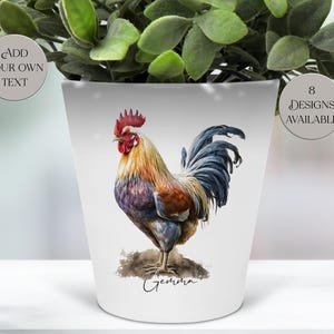 May include: A white ceramic plant pot decorated with a vibrant rooster design. The rooster is depicted with red, yellow, blue, and purple plumage. The pot has the name "Gemma" and the text "Add Your Own Text" and "8 Designs Available".