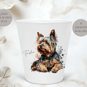 Peut inclure: Un mug en céramique blanche avec une illustration aquarelle d'un Yorkshire Terrier. Le nom Tasha est imprimé en écriture noire à côté du chien. Deux badges gris circulaires sur le mug indiquent ADD YOUR OWN TEXT et 8 DESIGNS AVAILABLE.