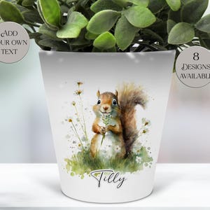 May include: White ceramic plant pot featuring a watercolor illustration of a squirrel holding a sprig of flowers. The pot has the name "Tilly" written on it. The text "Add Your Own Text" and "8 Designs Available" are also visible.