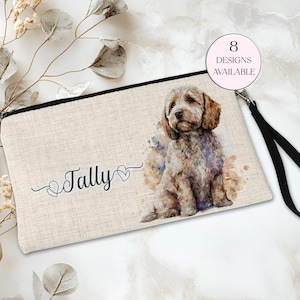 May include: A beige zipped pouch with a watercolour illustration of a dog. The pouch has a black zip and wrist strap. The name "Tally" is printed on the pouch, along with the text "8 Designs Available".