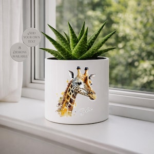 Könnte beinhalten: Weißer Keramik-Pflanztopf mit einem Aquarell-Giraffen-Design in Braun- und Gelbtönen. Er enthält eine grüne Sukkulentenpflanze. Auf dem Topf steht "Sasha". Auf der linken Seite steht "Fügen Sie Ihren eigenen Text hinzu" und "8 Designs verfügbar".
