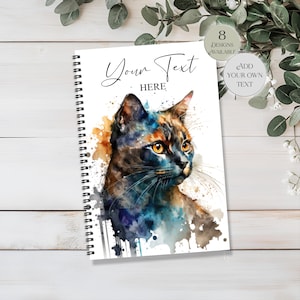 May include: A spiral-bound notebook with a watercolour painting of a cat in shades of orange and blue. The cover has the text "Your Text Here" and options to add text. 8 designs are available.