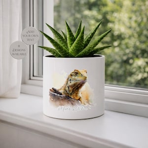 May include: White ceramic plant pot with a watercolour illustration of a lizard and a succulent plant. The pot has the text "Mum's Kitchen" and the option to add your own text. Eight designs are available.