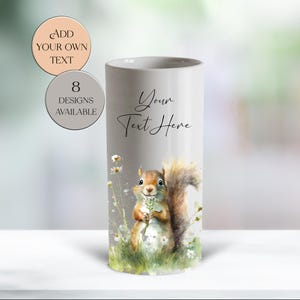 May include: A cylindrical, light gray tumbler with a watercolor illustration of a squirrel holding flowers. The words "Your Text Here" are written on the tumbler. Additional text on the image reads "Add Your Own Text" and "8 Designs Available."